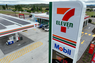 A 7-Eleven store assistant talks to a customer in-store.