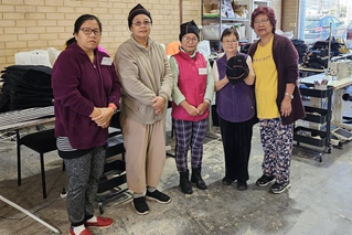 A picture of Loop Upcycling participants, holding beanies made from old 7-Eleven uniforms.